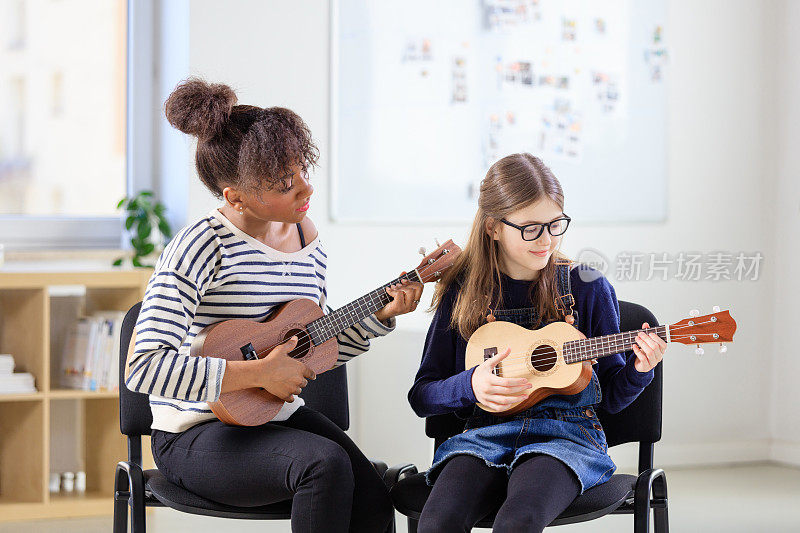 教练教女孩在课堂上弹奏尤克里里