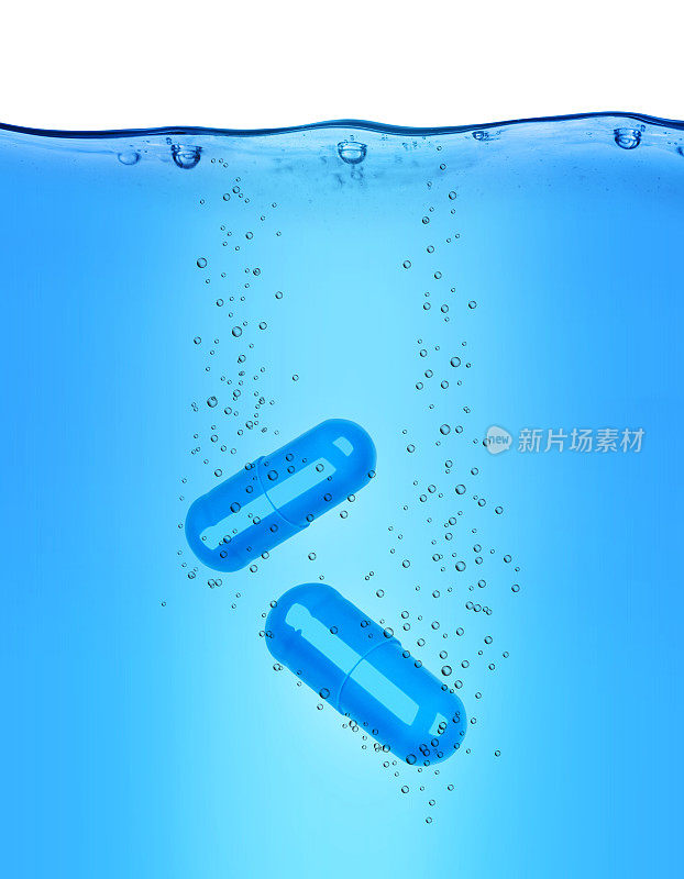 两个医疗胶囊溶解在蓝色的水中