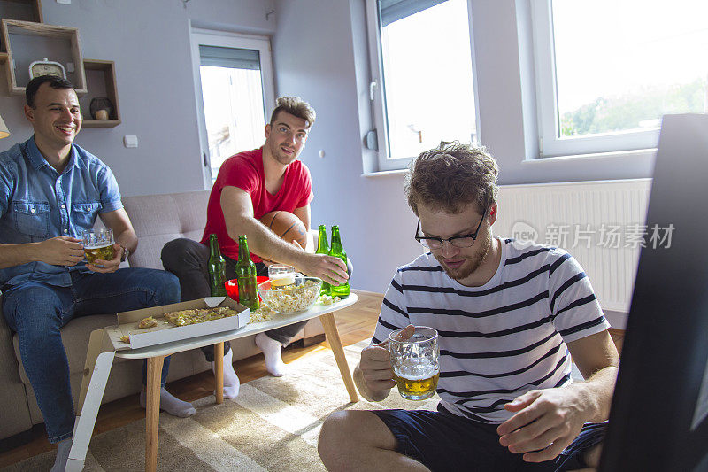 年轻的男性在家看篮球比赛喝啤酒