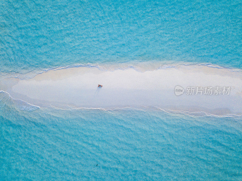 一对年轻的成年夫妇一起躺在马尔代夫碧绿的沙滩上