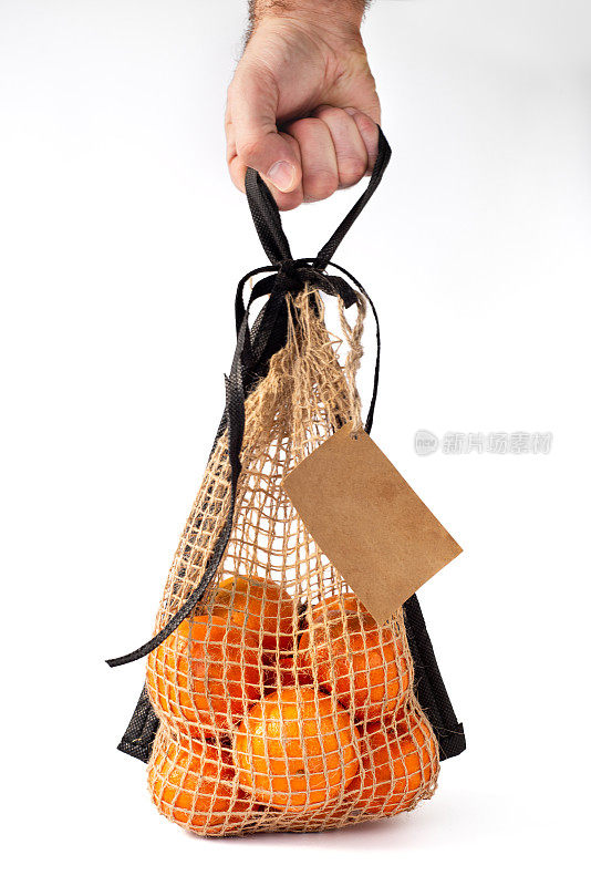 拿包。柑橘类水果在一个自然材料网格在白色的背景与地方为文本。Eco-packaging。明亮的橙色的橘子。自然光线。