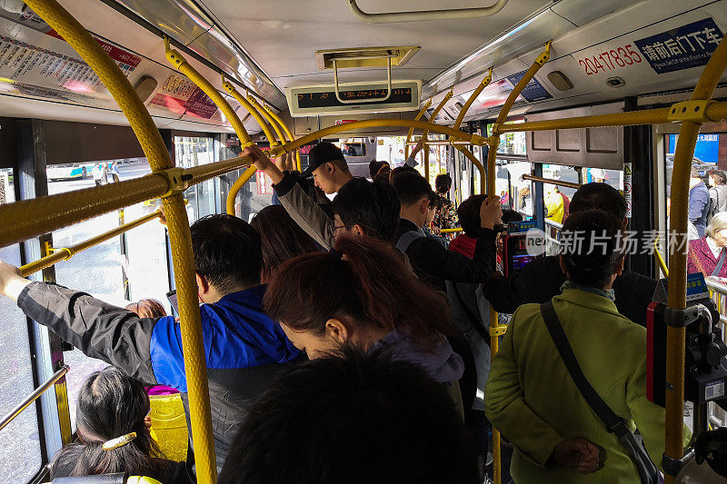 在中国北京，人们在工作日的早上挤着公交车去上班。