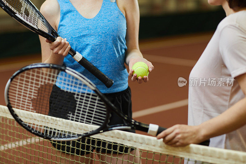 特写的妇女与球拍站在网球网和选择谁将投球网球