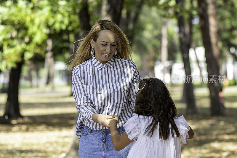 妈妈和她的可爱的女儿正在公园里享受