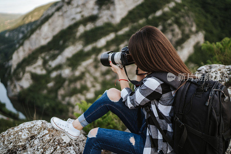 年轻的女摄影师在大自然中拍照
