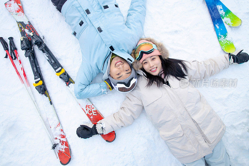 快乐的青年伴侣躺在雪地上