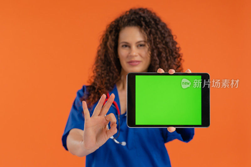 美丽的女医生显示数字平板与色度键绿色屏幕，OK标志，积极的情绪