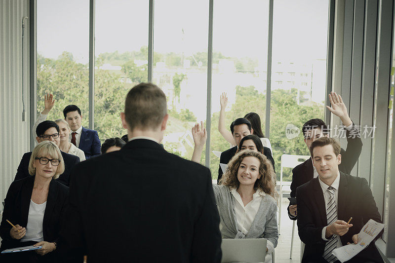 商务人士在会议中与演讲者举手提问，在会议中举手同意或投票表决意见