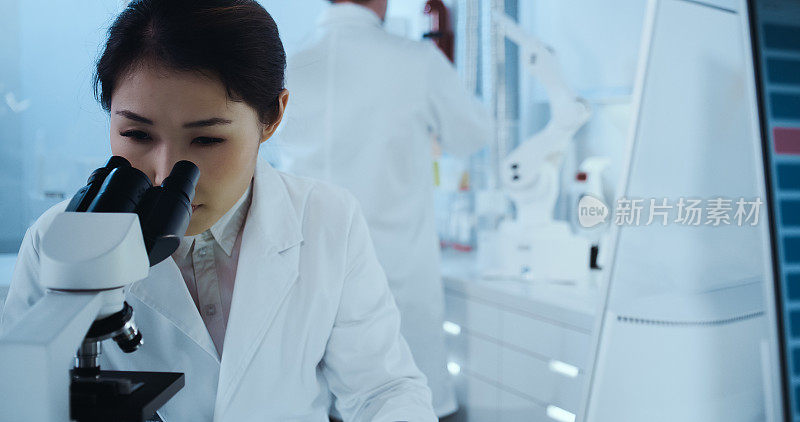 laboratorr遗传研究。亚洲女医生使用显微镜，研究伙伴背景