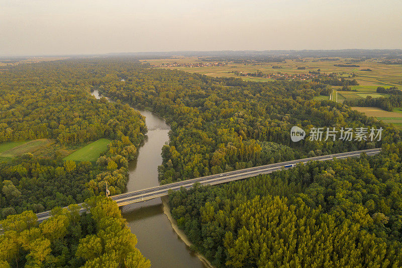 鸟瞰图的河流和道路通过森林在阴沉的日出