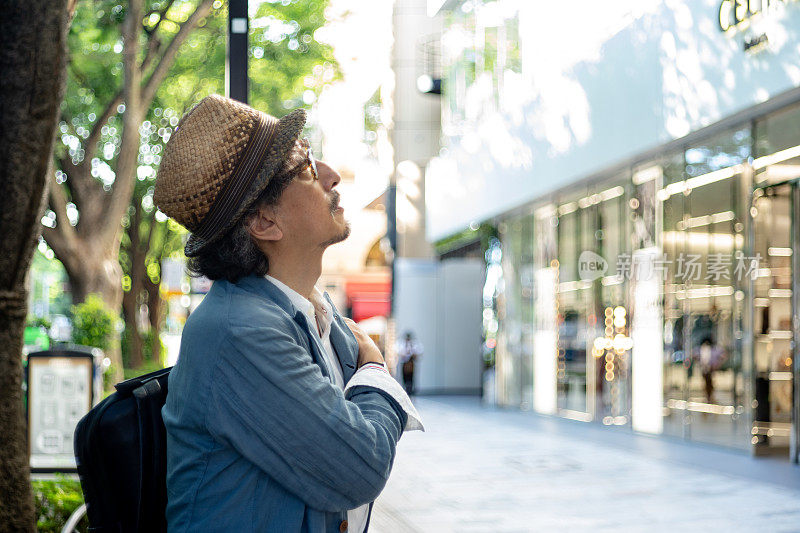 在东京表参道的一条绿树成荫的街道上，一位老人正在等待会议