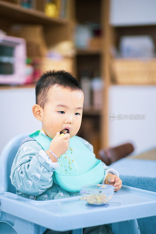 小男孩坐在高椅子上吃东西