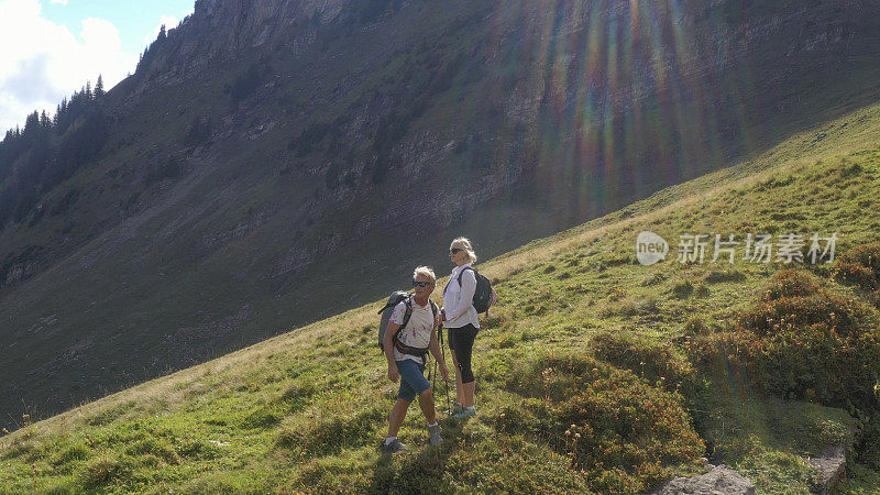 鸟瞰图的徒步旅行夫妇穿越高山草地，在日出