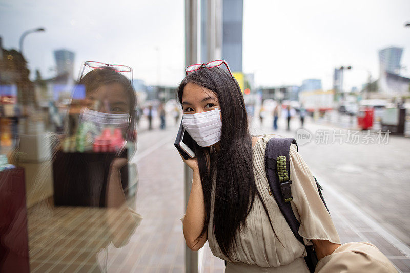 女人戴着保护面罩在城市里打电话