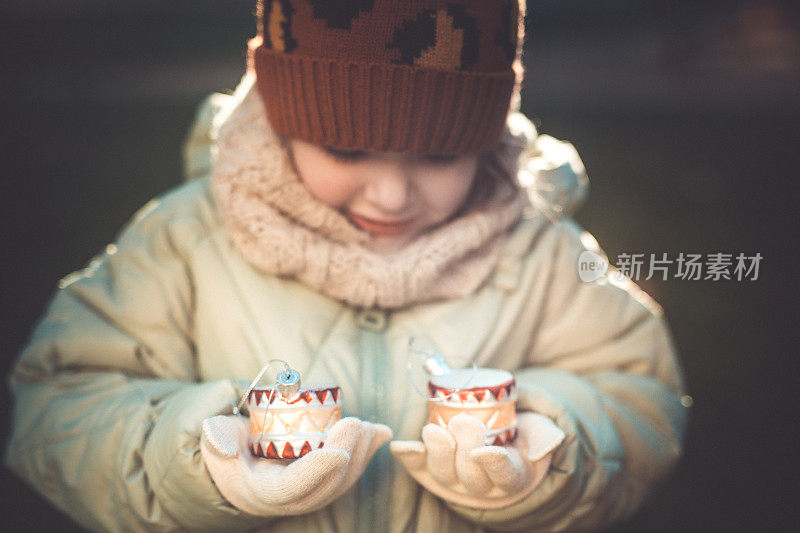 一个学龄前的小女孩手里拿着盒子里的圣诞装饰品