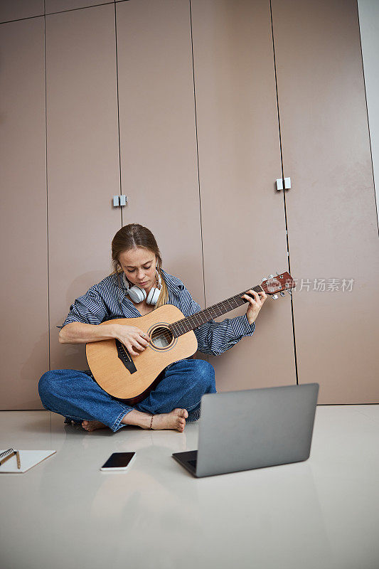 年轻漂亮的女人在家里弹吉他