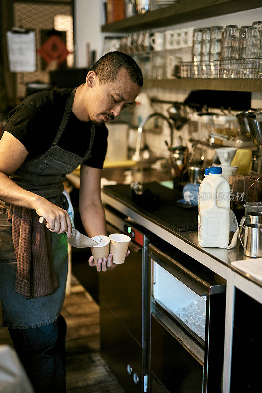 亚洲咖啡馆老板在咖啡店的照片。年轻的亚洲咖啡师正在制作冰咖啡。