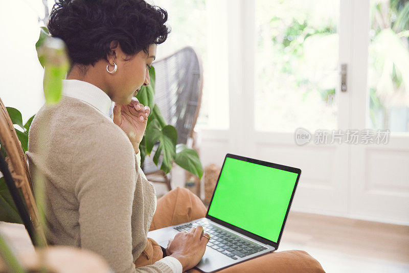 年轻女子在她的绿屏电脑上无缝工作，从舒适的家中制作魔法
