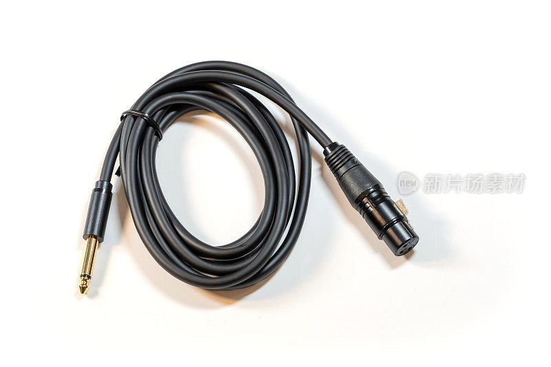 卷曲的黑色音频电缆，一端是14英寸插孔，另一端是XLR公连接器，隔离在白色背景上，没有人。专业麦克风麦克风工作室电缆对象，没有人