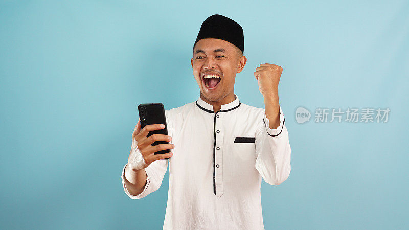 一名穆斯林男子兴奋地从电话中得到好消息，在蓝色背景上庆祝成功