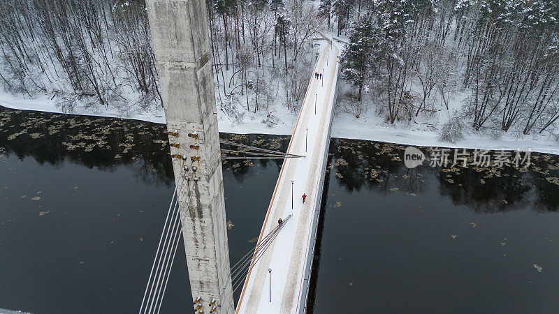 无人机拍摄的积雪覆盖的混凝土人行桥和冬日行人过街