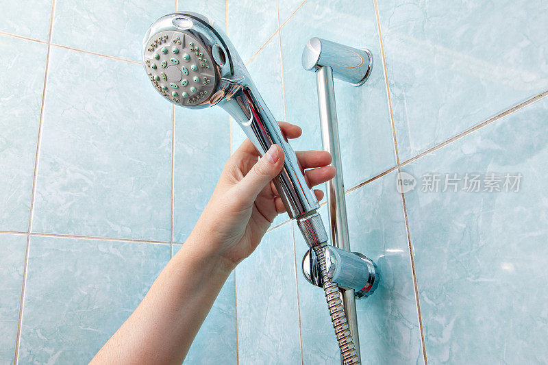 人的手的特写调节支架淋浴喷头与软管。
