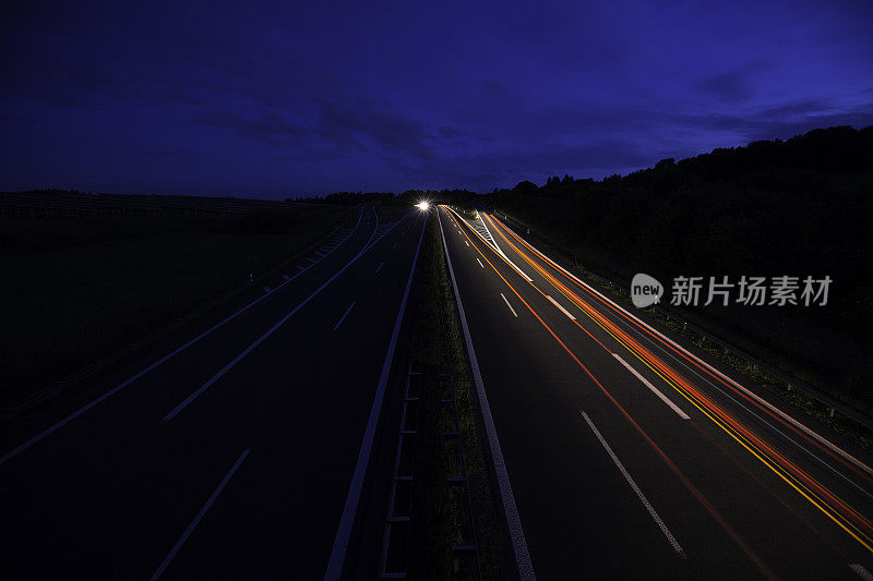 公路上的夜晚:夜幕降临后，公路上出现了灯光