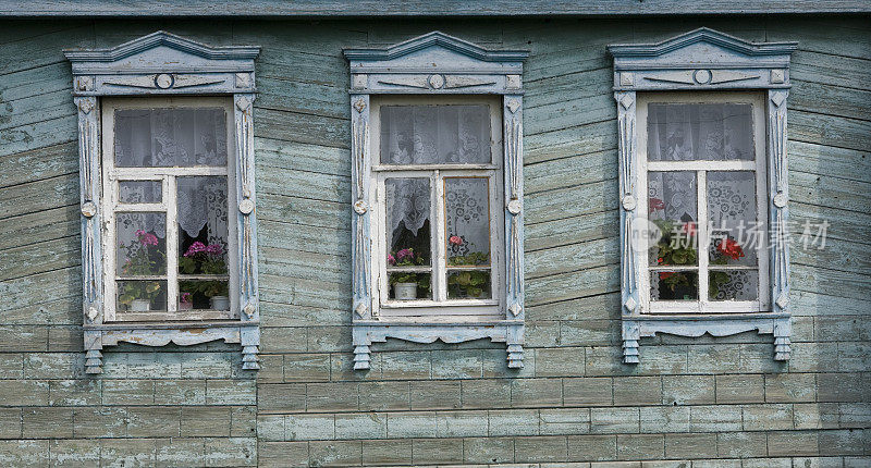 三扇古老的木制窗户展示着来自俄罗斯的红色天竺葵