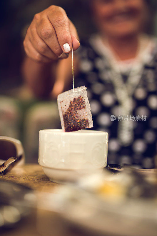 一个面目全非的人把茶包从杯子里拿出来。