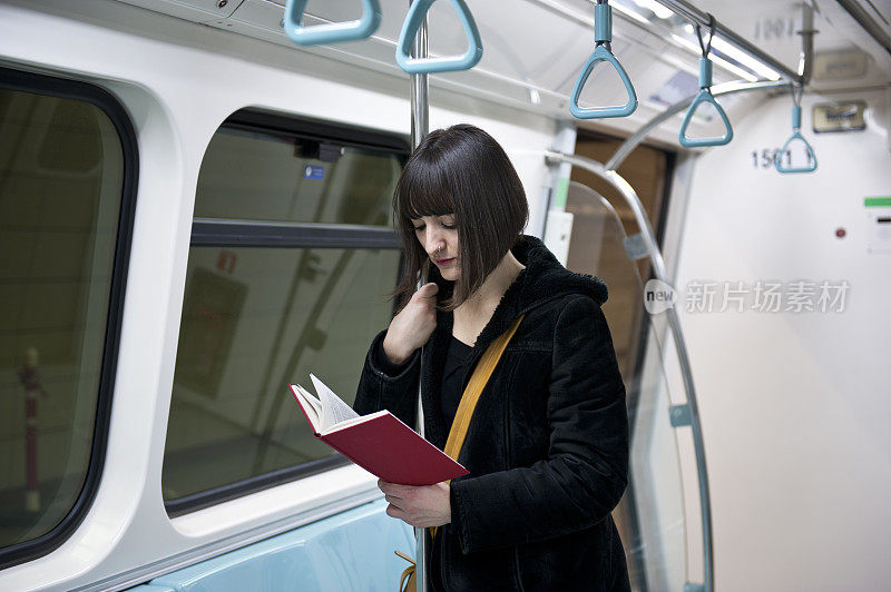 年轻女子在地铁上看书