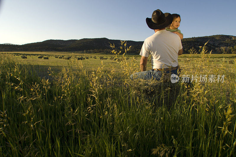 在捆草地里，农夫拥抱着儿子
