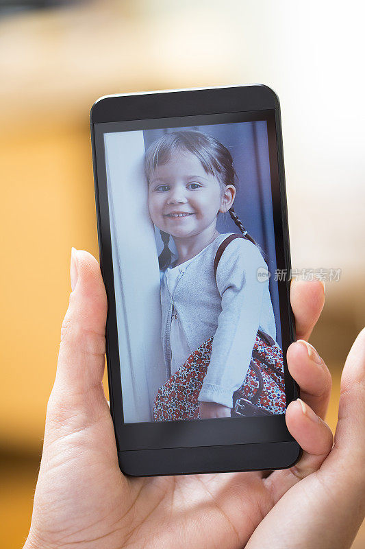 女人拿着智能手机展示孩子的照片