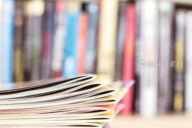 边缘的彩色杂志堆放与模糊的书架