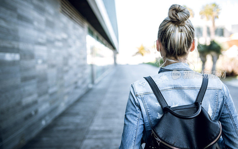 年轻女子背着背包走在欧洲的街道上