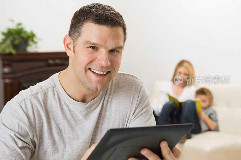 父亲在家里和家人一起使用数字平板电脑