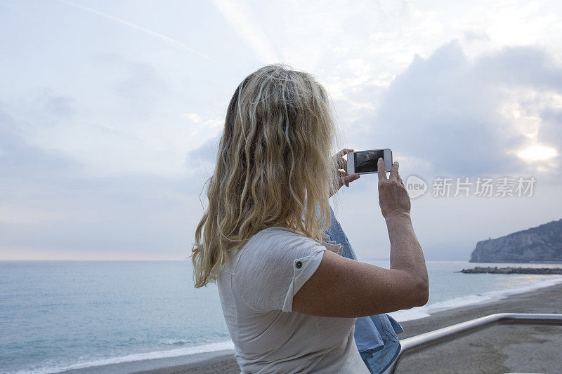 女人从海上休息的地方拍照