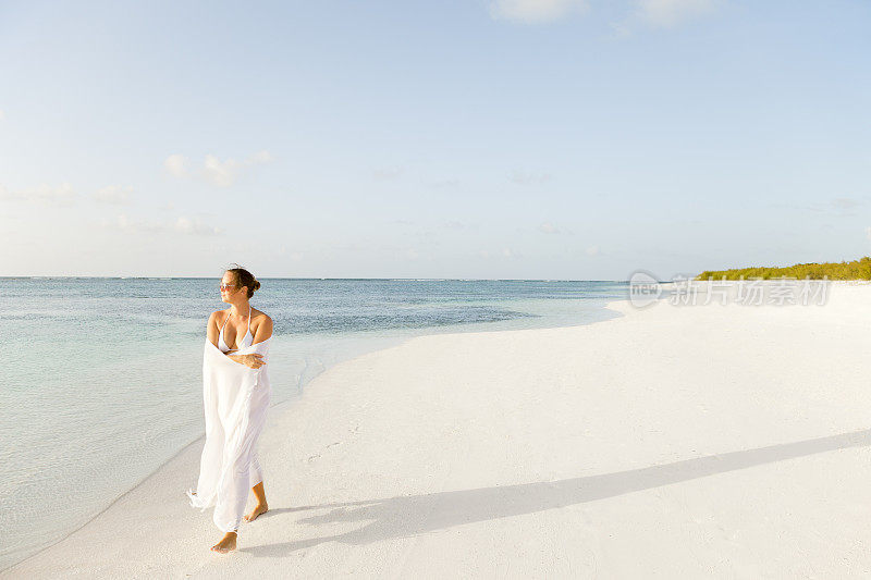 一个穿着白色衣服的女人在加勒比海的热带海滩上