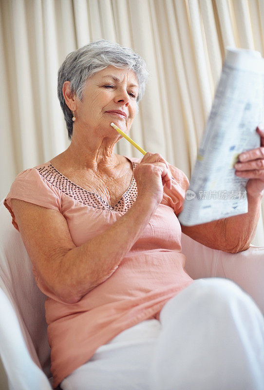 一位深思熟虑的老妇人正在解报纸上的填字游戏
