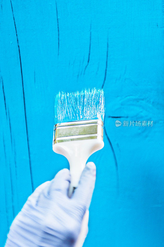 用刷子在木板上刷蓝色油漆