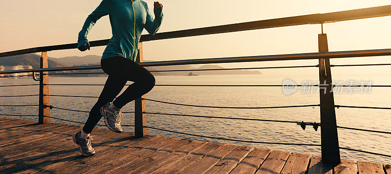 年轻的健身妇女跑步在日出的海滨木板路