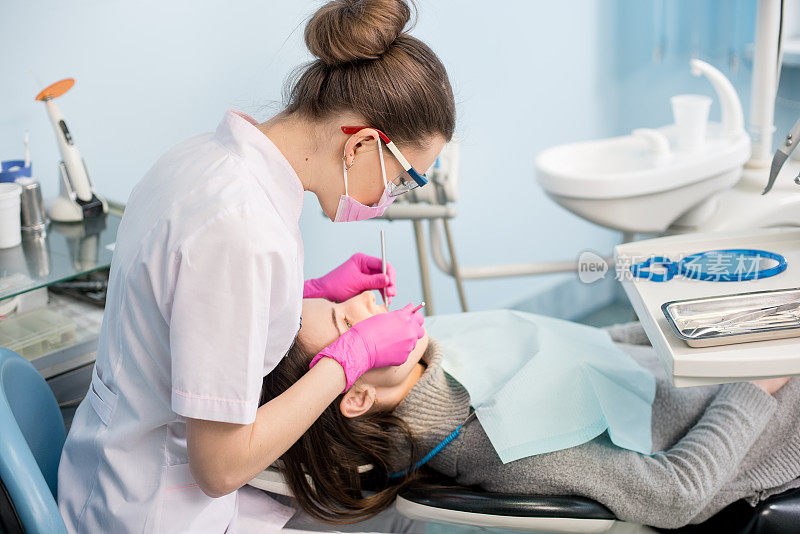 女牙医用牙科工具-镜子和探针在牙科诊所治疗病人的牙齿。医学、牙科和保健概念。牙科设备