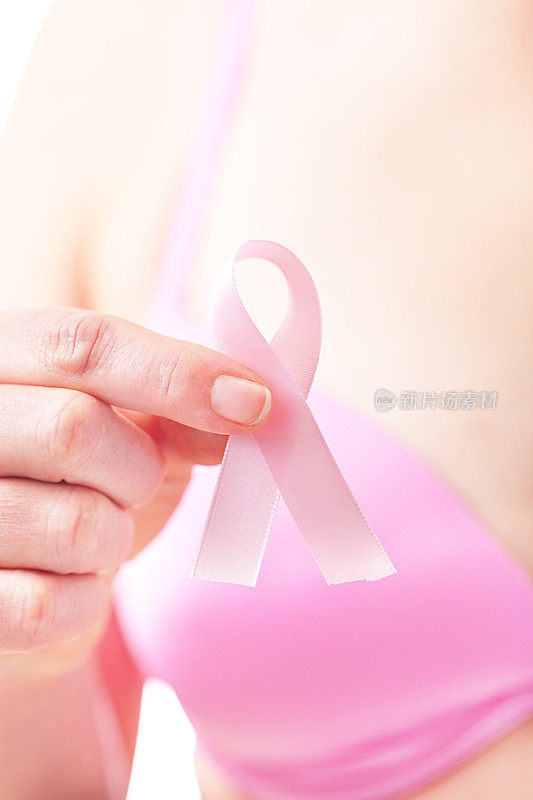 妇女拿着乳腺癌意识丝带，粉色健康检查提醒