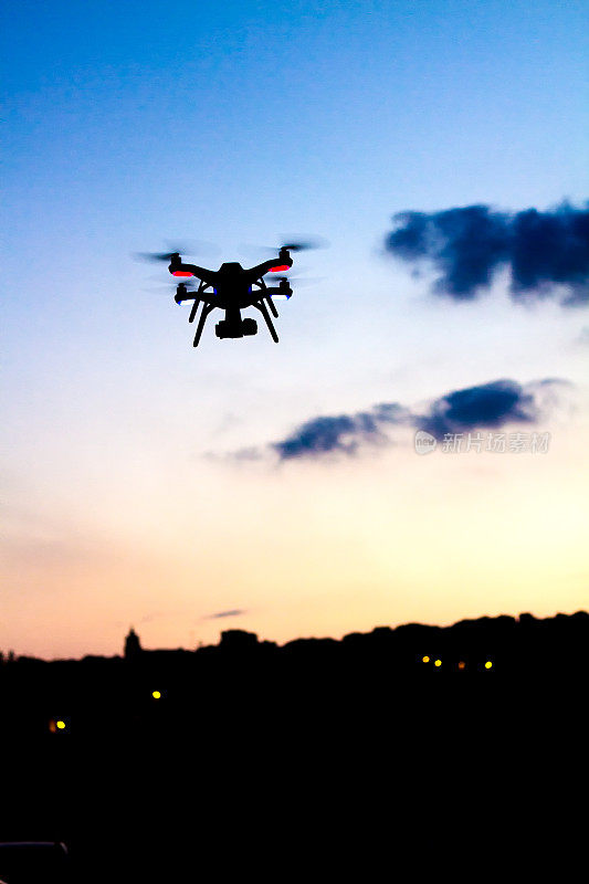 带摄像头的小型无人机在日落时飞行，远处的天际线