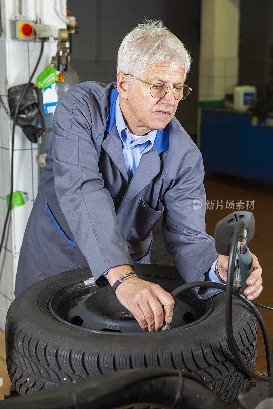 在汽车修理厂…汽车修理工正在检查轮胎气压