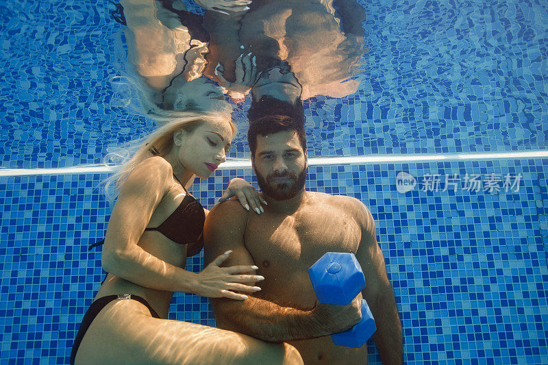 水下女子和男子在游泳池用哑铃训练