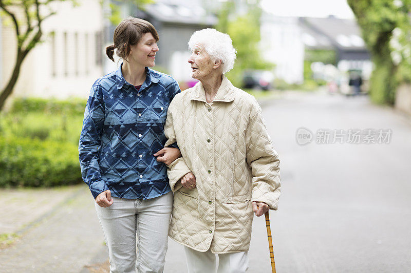 年轻的看护者帮助在街上行走的老年妇女