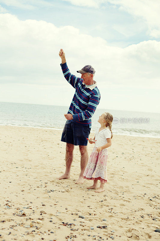 小女孩和爷爷在海滩上放风筝