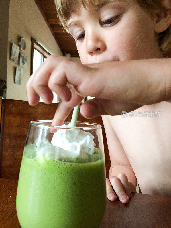 男孩喝着绿色的，健康的奶昔