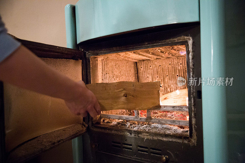 女人把木头放在烧木头的炉子上