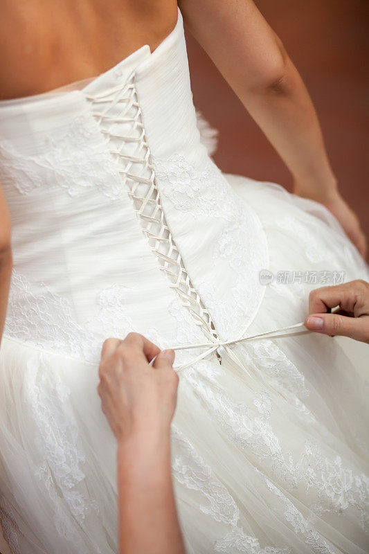 伴娘帮新娘穿上婚纱。